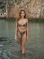 A girl wearing the Amarelle bikini, embracing the beach vibes and the vibrant patterns of her swimsuit while enjoying the refreshing ocean breeze