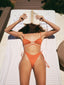 A girl wearing Amarelle bikini, sitting on the beach, reading a book